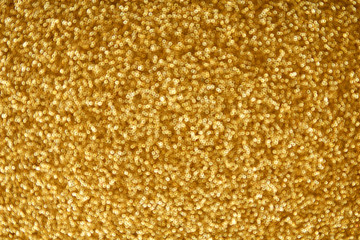 Gold glitter texture sparkling paper background. Abstract twinkled golden glittering background  with bokeh, defocused lights for Christmas holiday, banner, wedding invitation and greeting cards.