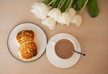 view above of cup with cacao and saucer on the table, white tulips; morning Breakfast with cacao