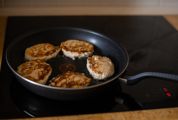 homemade cheesecakes are fried in a frying pan, the process of cooking homemade cheesecakes on a ceramic plate