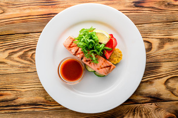 salmon with salad and vegetables - dish on a wooden background