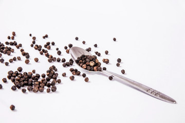 organic black pepper and metal spoon