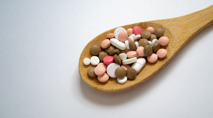 Mixed medicine pills, tablets on wooden spoon on white background with space for text. Different pills and tablets. Pharmaceutical pills and tablets. Flat lay of medicine pills and tablets