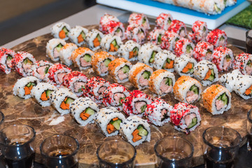 Colorful assortment of sushi rolls on a marble plate during brunch buffet or catering event