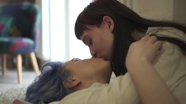 two homosexual woman kissing gently while lying bed floor Spbd. calm serene relationship. woman intimate same sex couple concept. sensual kissing on apartment floor