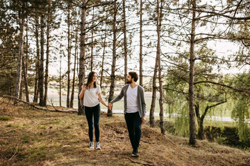 Fototapeta premium Young happy married couple walking in a forest in mountains, holding hands.