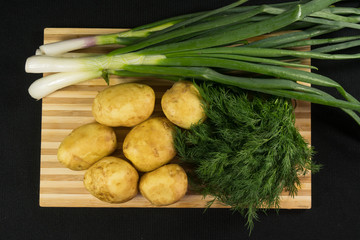 Obraz na płótnie Canvas Raw fresh organic potatoes on black wooden table against dark background.