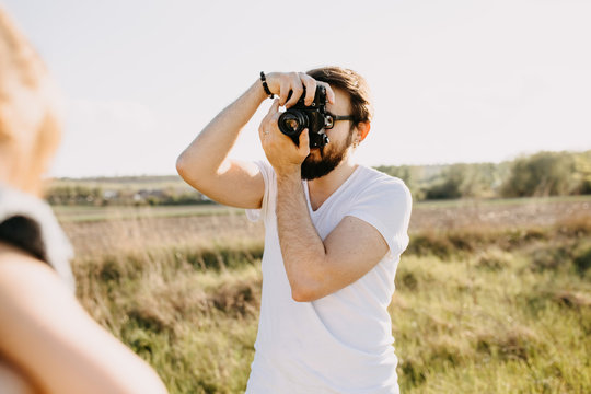 Young bearded hipster man taking photos with a vintage film camera, outdoors.