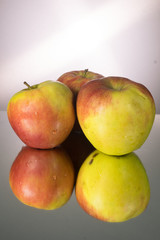 Three red apple on mirroring table. Vertical image with copy space.