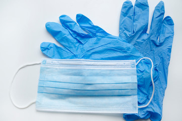 Blue medical mask and pair of surgery gloves on white background