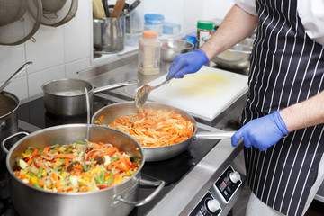 Man in apron and gloves cooking fresh vegetables for healthy food