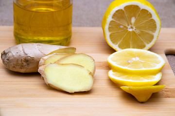 sliced slices of ginger lemon and honey on a wooden board on a sackcloth background.