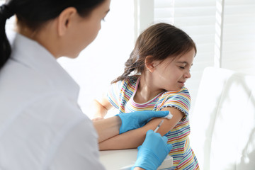 Fototapeta premium Doctor vaccinating little child in modern clinic