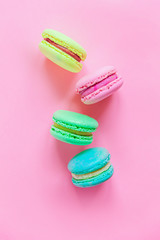 Obraz premium Sweet almond colorful pink blue yellow green macaron or macaroon dessert cake isolated on trendy pink pastel background. French sweet cookie. Minimal food bakery concept. Flat lay top view, copy space