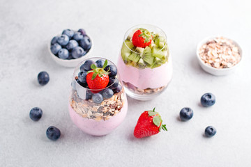 Fototapeta na wymiar Chia seeds pudding with granola, blueberry and strawberry in glasses. Yogurt with chia seeds, berries, kiwi and muesli for healthy breakfast, copy space