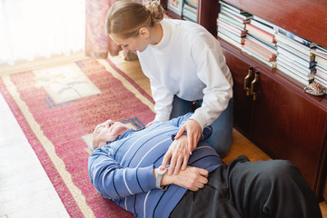 Nurse in assisting living program finding senior lying on the floor