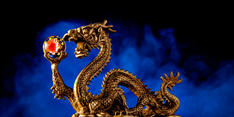 Chinese Dragon holding a Chrysanthemum Sphere with a smokey red background,  blue symbolizing immortality and advancement. Blue also represents the season of Spring