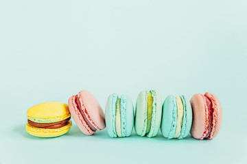 Sweet almond colorful pink blue yellow green macaron or macaroon dessert cake isolated on trendy blue pastel background. French sweet cookie. Minimal food bakery concept. Flat lay top view, copy space