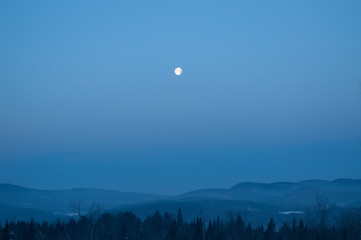Landscape view of Vermont during sunrise with the moon and a beautiful forest