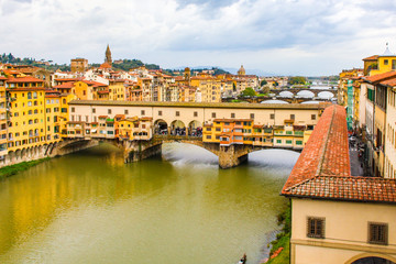 Obraz premium Veduta di Ponte Vecchio sul fiume Arno, Firenze, Italia, con cielo nuvoloso.