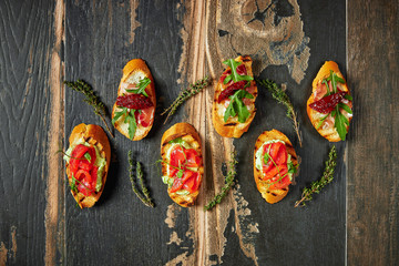 Traditional Bruschetta with Parma dried ham and prosciutto. Italian antipasti set sandwiches on a rustic wooden Board Top view