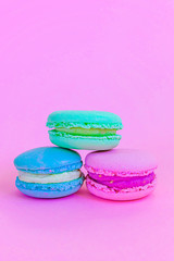 Sweet almond colorful unicorn blue green pink macaron or macaroon dessert cake isolated on trendy pink pastel background. French sweet cookie. Minimal food bakery concept Copy space