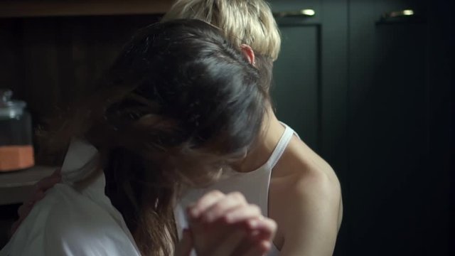Affectionate lesbian couple hugging and kissing while sitting on kitchen floor. Spbd two woman share sensual embrace. girlfriend, loving, happy concept. same sex relationship