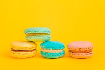 Sweet almond colorful unicorn pink blue yellow green macaron or macaroon dessert cake isolated on trendy yellow modern fashion background. French sweet cookie. Minimal food bakery concept Copy space