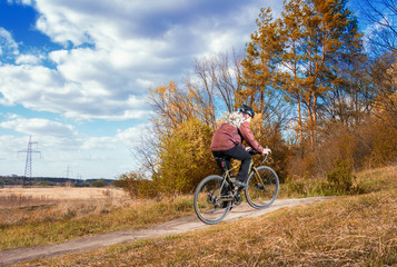 Fototapeta premium Gravel bike. Cyclist on a gravel bike rides along a path into the forest. Active lifestyle.