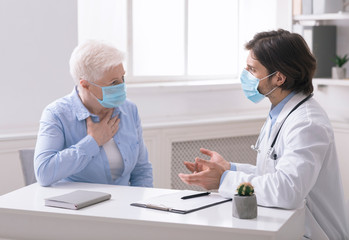 Doctor consulting senior woman with cough, in office