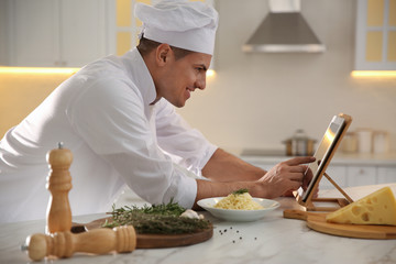 Chef with tablet cooking at table in kitchen
