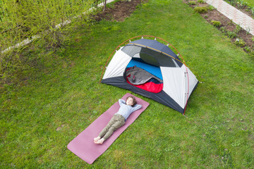 Dreams about travel during coronavirus quarantine. Cute curly boy laying on the grass by the tent...