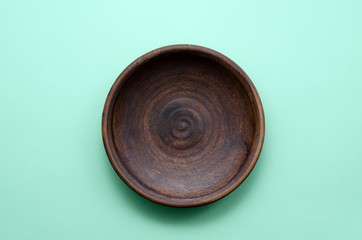 Empty brown ceramic dishware plate on a light green background. The concept of food and its absence. blank for food with place for text
