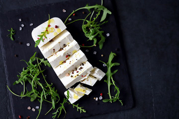 Selective focus. Macro. Sliced feta cheese with seasonings and olive oil. Greek feta cheese on a stone board. Keto snack. Healthly food.