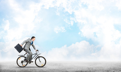 Man wearing business suit riding bicycle outdoor.