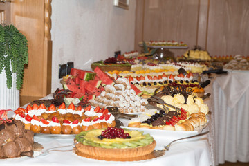 buffet with sweets. fruits and other sweets on dessert table. Rows of tasty looking desserts in beautiful arrangements. Sweets on banquet table - picture taken during catering event