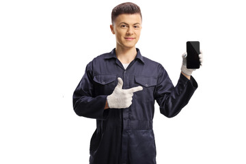 Young mechanic holding a mobile phone and pointing