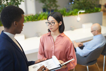 High angle view at young Asian businesswoman talking to partner while discussing project in modern office, copy space