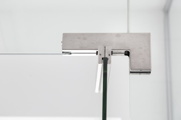 glass door hinges to bathroom, close up of hinged accessories of transparent partitions on the white wall front view.
