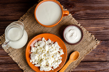 Homemade fermented milk products - kefir, cottage cheese on burlap on a wooden background.