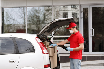 Quarantine and home delivery concept. Courier open trunk of car, takes out parcel