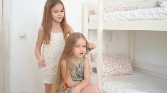 little girl brushing hair of her younger sister
