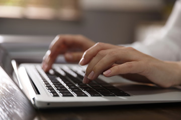 Woman working with laptop in office, closeup of hands