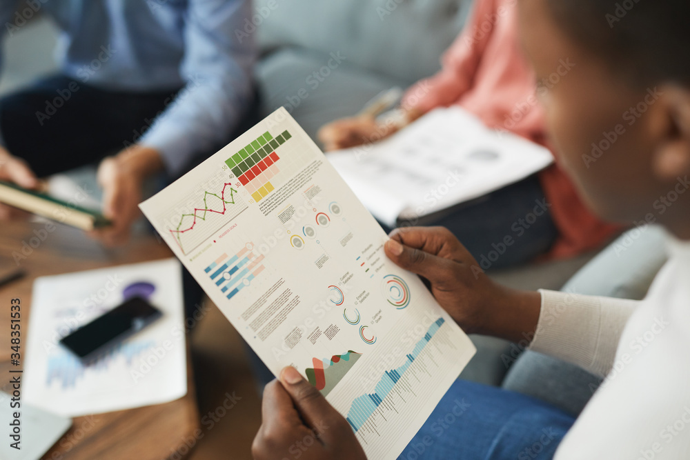 Wall mural high angle view of unrecognizable businessman holding statistics report while working on startup pro