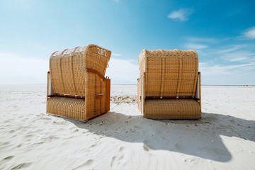 Two wicker chairs on a sandy tropical beach