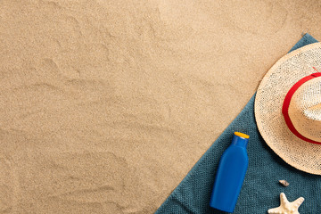 Top view of sandy beach with towel frame and summer accessories. Background with copy space and visible sand texture. Border composition made of towel