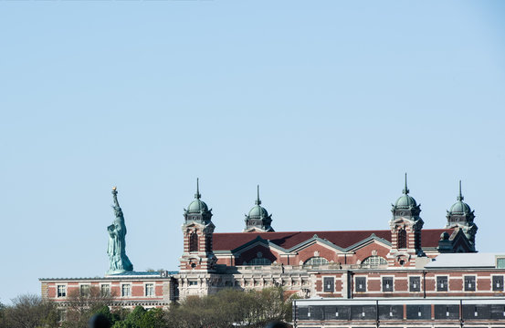 Side view of statue of liberty and the exterior of ellis island on the Hudson River, taken from the Liberty State Park.