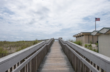 Outdoor wooden boardwalk walkway, with sky and cloud background.  Beach cabana pier plank bridge. - 348353924