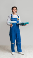 Professional Painter In Work Uniform Holding Paint Roller And Smiling At Camera