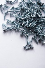 Steel screws randomly lie on a white background. Necessary parts for the assembly of furniture. Repair topic