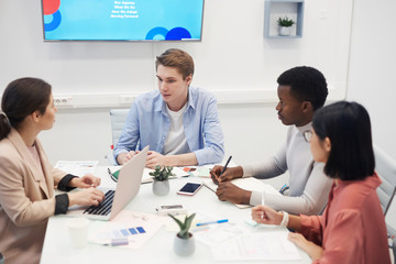 High angle view at young man heading business meeting with multi-ethnic group of people in office, copy space